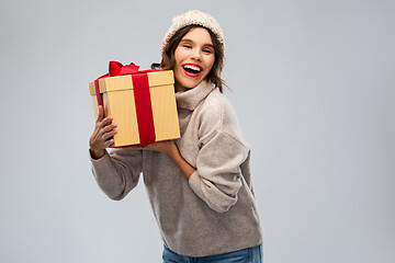 Image showing young woman in knitted winter hat holding gift box