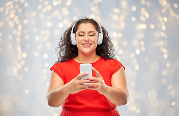 Image showing woman in headphones listens to music on smartphone