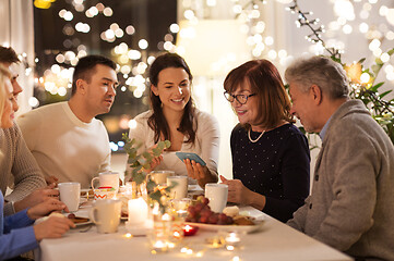 Image showing happy family with smartphone at tea party at home