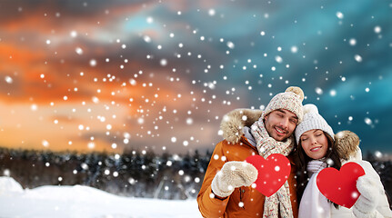 Image showing happy couple with red hearts over winter landscape