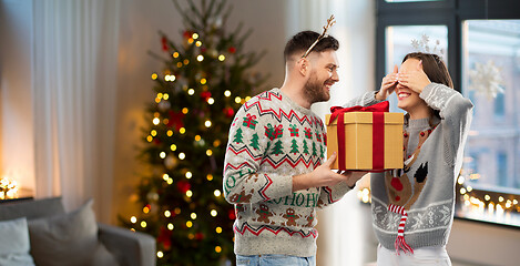 Image showing happy couple in christmas sweaters with gift box