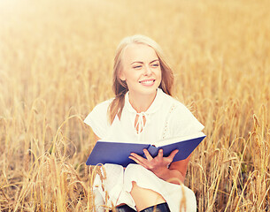 Image showing smiling young woman reading book on cereal field