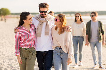 Image showing happy friends walking along summer beach