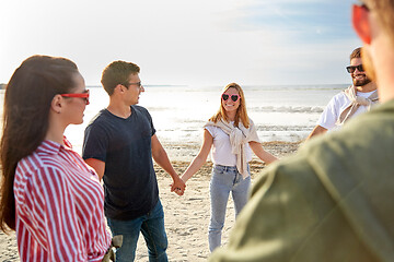 Image showing happy friends holding hands on summer beach