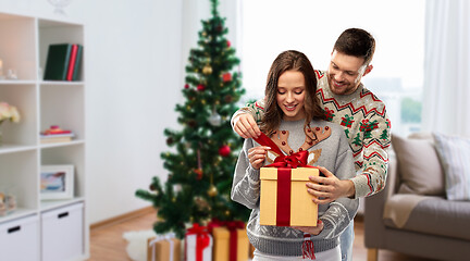 Image showing happy couple in christmas sweaters with gift box