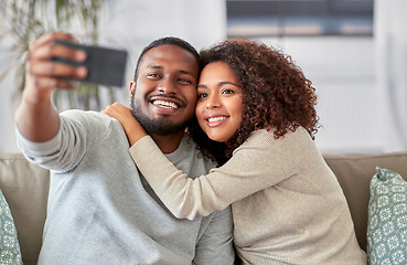 Image showing happy couple with smartphone taking selfie at home