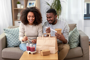 Image showing happy couple with takeaway food and drinks at home