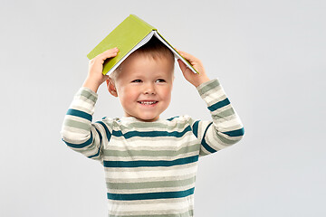 Image showing portrait of smiling boy with book on head