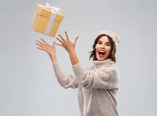 Image showing young woman in winter hat catching gift box