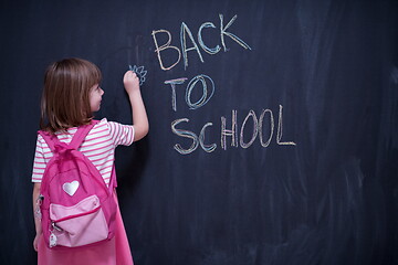 Image showing school girl child with backpack writing  chalkboard