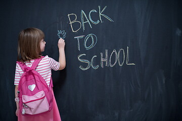 Image showing school girl child with backpack writing  chalkboard