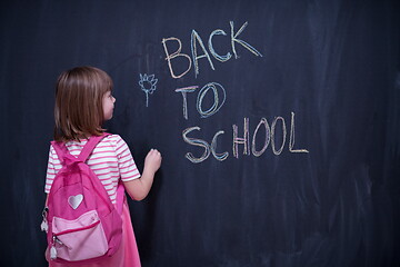 Image showing school girl child with backpack writing  chalkboard