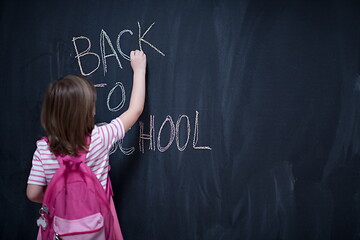 Image showing school girl child with backpack writing  chalkboard