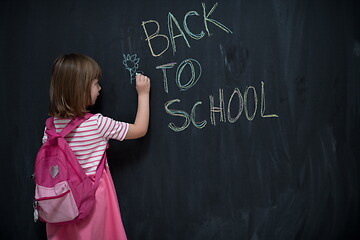 Image showing school girl child with backpack writing  chalkboard