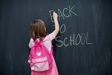 Image showing school girl child with backpack writing  chalkboard