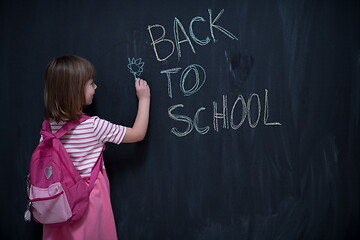 Image showing school girl child with backpack writing  chalkboard