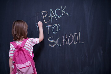 Image showing school girl child with backpack writing  chalkboard