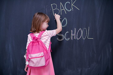 Image showing school girl child with backpack writing  chalkboard