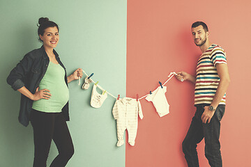 Image showing young couple holding baby bodysuits