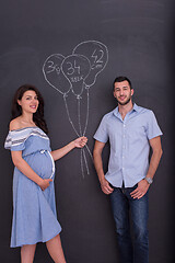 Image showing pregnant couple drawing their imaginations on chalk board