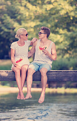 Image showing couple enjoying watermelon while sitting on the wooden bridge