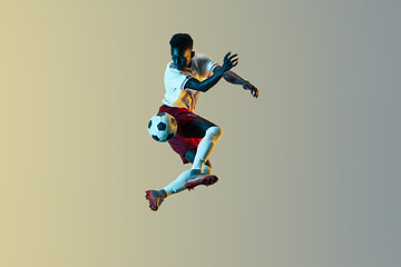 Image showing Male soccer player kicking ball in jump isolated on gradient background