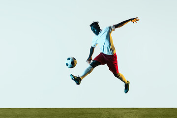 Image showing Male soccer player kicking ball isolated on white background