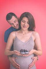 Image showing young pregnant couple holding newborn baby shoes