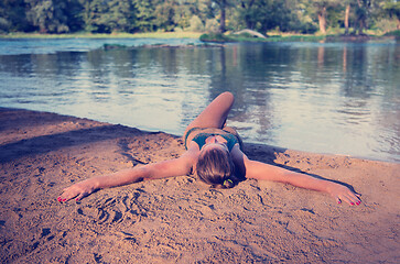 Image showing girl in a green bikini relaxing on the riverbank