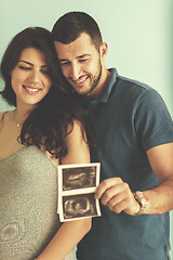 Image showing couple looking ultrasound picture isolated on blue background