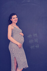 Image showing Portrait of pregnant woman in front of black chalkboard