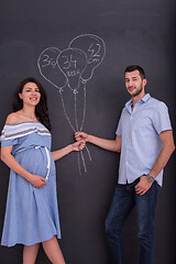 Image showing pregnant couple drawing their imaginations on chalk board