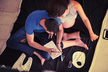 Image showing top view of couple checking a list of things for their unborn ba