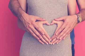 Image showing pregnant  couple showing heart with their hands