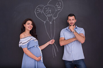 Image showing pregnant couple drawing their imaginations on chalk board