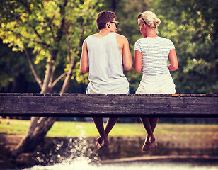 Image showing couple enjoying watermelon while sitting on the wooden bridge