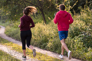 Image showing young couple jogging along a country road