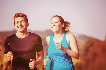 Image showing young couple jogging along a country road