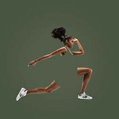 Image showing Young african woman running or jogging isolated on green studio background.