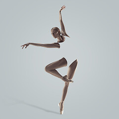 Image showing Ballerina. Young graceful female ballet dancer dancing over grey studio. Beauty of classic ballet.