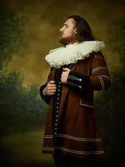 Image showing Young man as a medieval knight on dark background