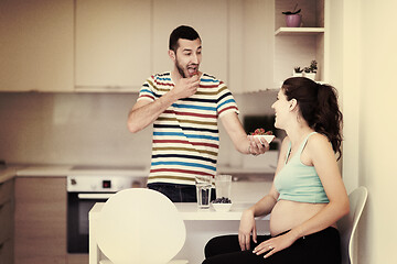 Image showing couple eating fruit strawberries at kitchen