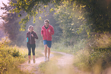 Image showing young couple jogging along a country road