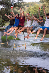 Image showing friends enjoying watermelon while sitting on the wooden bridge