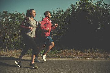 Image showing young couple jogging along a country road