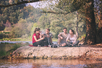 Image showing friends smoking hookah on the river bank