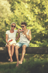 Image showing couple enjoying watermelon while sitting on the wooden bridge