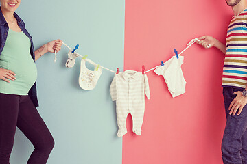 Image showing young couple holding baby bodysuits