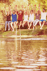 Image showing friends enjoying watermelon while sitting on the wooden bridge