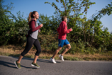 Image showing young couple jogging along a country road